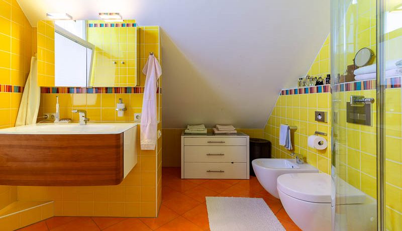 Bunt geflieste Wände für viele bunte Erinnerungen: das Badezimmer im Spitzboden erleichtert Ihren Alltag
