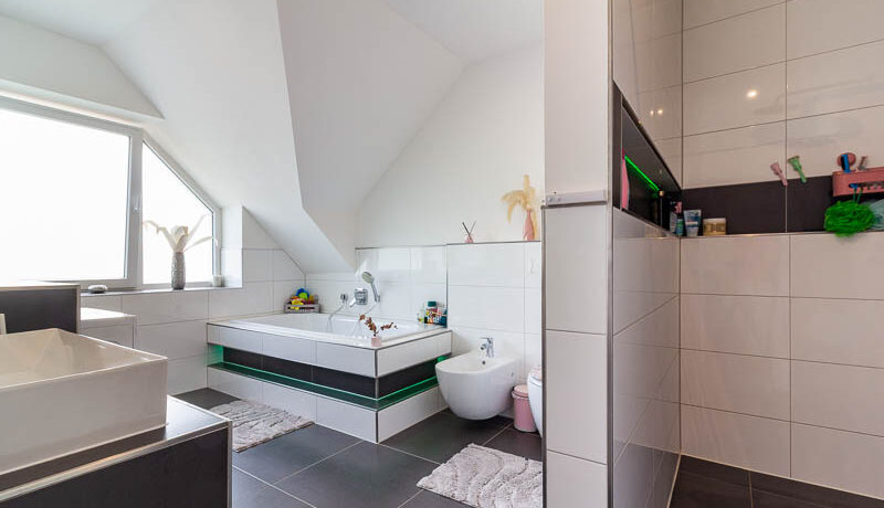 Elegantes Badezimmer mit klaren Linien, großformatigen Fliesen und stimmiger Lichtgestaltung.