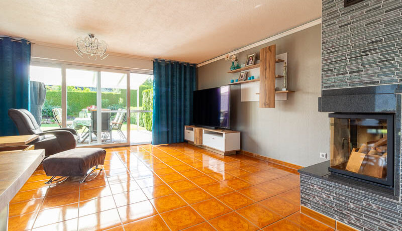 Wohnzimmer mit bodentiefen Fenstern, Blick in den Garten und Zugang zur überdachten Terrasse – ein Wohnbereich mit Weitblick.