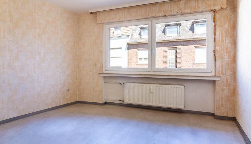 Helles Schlafzimmer mit großem Fenster – viel Potenzial für einen gemütlichen Rückzugsort.
