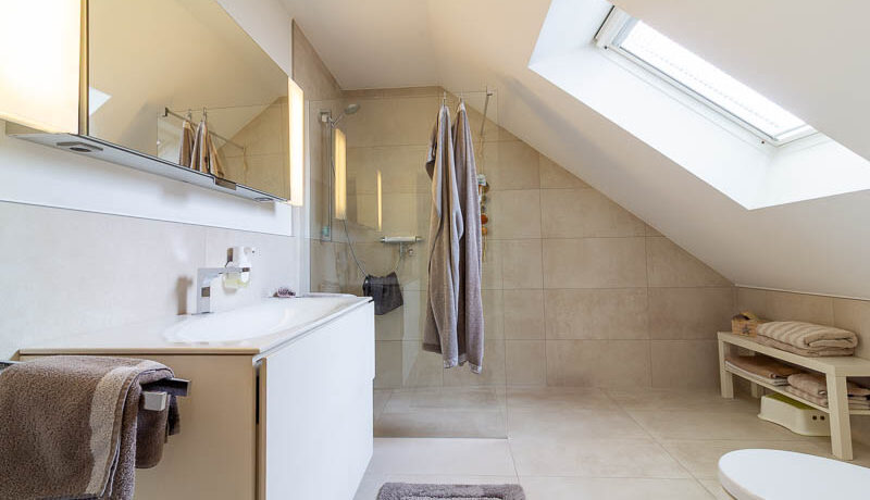 Das Schlafzimmerbad: Klar strukturiert, stilvoll modernisiert und mit großzügiger Dusche – ideal für den täglichen Komfort.