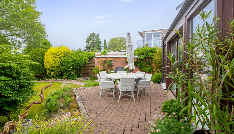 Die stilvolle Terrasse am Wintergarten bietet Raum für gesellige Abende und entspannte Stunden im Garten.