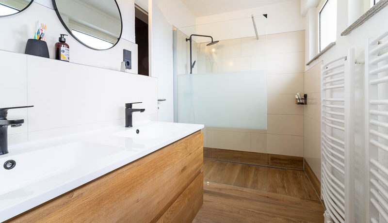 Modern, hell und komplett kernsaniert – das Badezimmer überzeugt mit begehbarer Dusche, Doppelwaschbecken und hochwertiger Ausstattung.